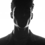 Dramatic silhouette of a man backlit against a bright white background.